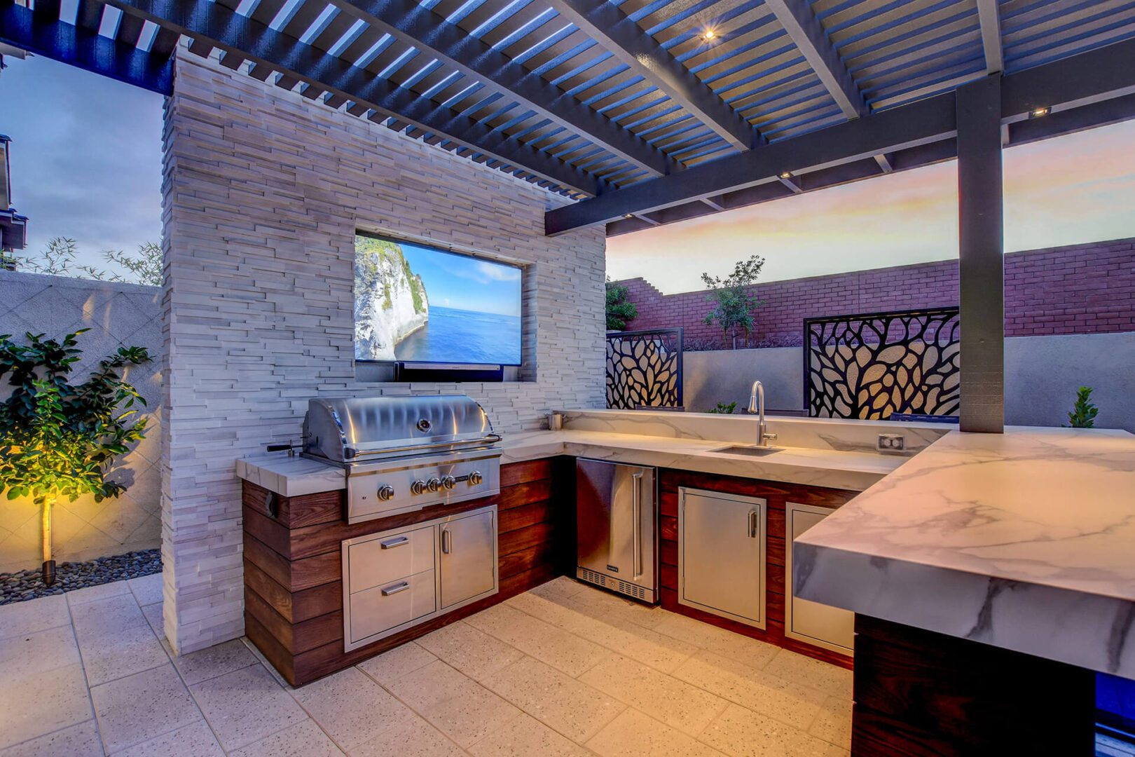 Dusk Photography of Custom Outdoor Kitchen and Outdoor Living Area with a Media Wall, and Patio by Custom Outdoor Living of Las Vegas, Nevada