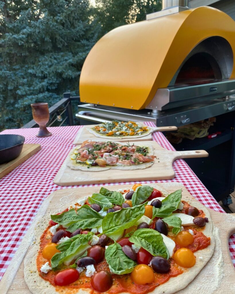 Fresh tomato and basil pizzas on paddles near oven